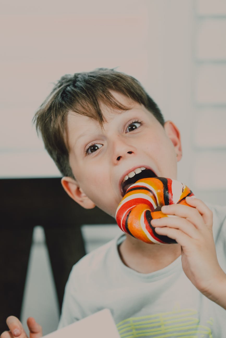 a boy eating a colorful bagel